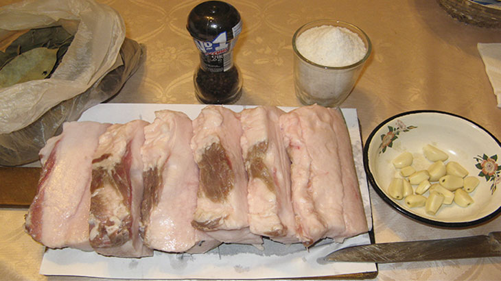 Фотография нарезанного свиного сала и ингредиентов перед засолкой.
